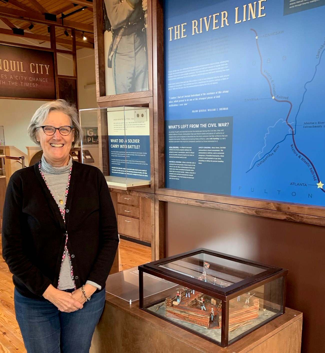 Margaret Jourden, The River Line Historic Area's Shoupade Park Coordinator, stands next to the River Line and Shoupade display at the Smyrna History Museum